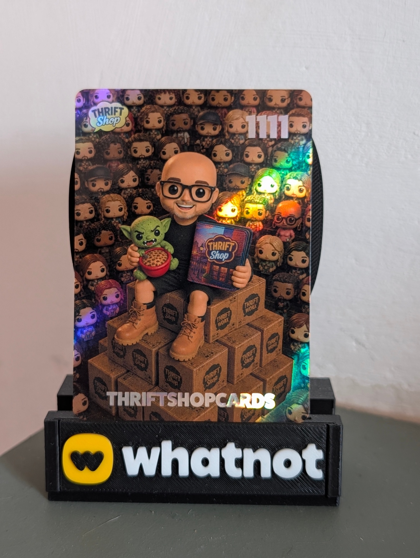 The current front design featured on card №1111 — a holographic hero portrait on a wall of Pop figures with the THRIFTSHOPCARDS wordmark.